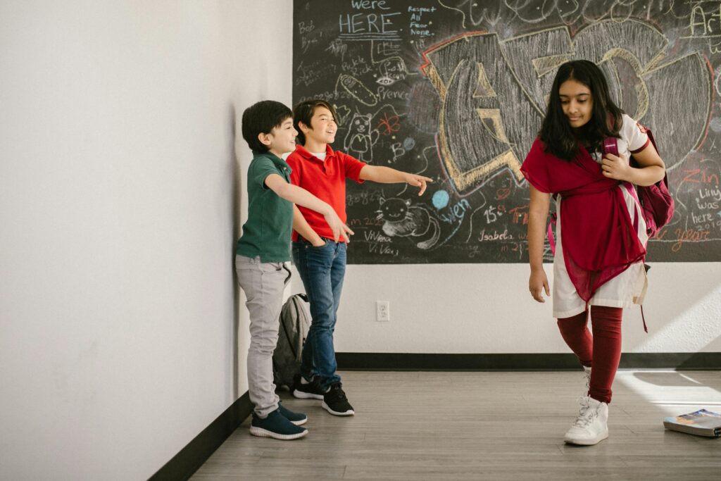 Children engaging in a bullying scene inside a school's hallway with chalkboard wall.